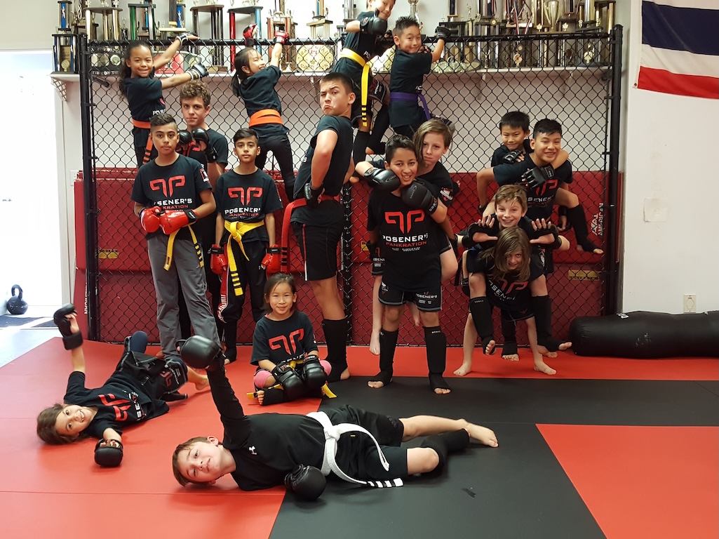 Group of kids training and posing at a martial arts gym in Vancouver, BC, wearing Posener's Pankration uniforms. The photo shows a fun, energetic atmosphere with children of different ages practicing MMA for kids in Vancouver or nearby areas.